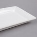 An American Metalcraft white rectangular stoneware platter on a gray surface.
