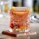 An Acopa Gardenia rocks glass filled with a drink and a slice of orange on top.