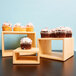 Three wooden display risers with cupcakes on them in a bakery display.