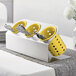 A Steril-Sil stainless steel flatware organizer with yellow perforated plastic cylinders holding silver utensils.