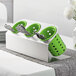 A Steril-Sil stainless steel flatware organizer with lime green plastic cups holding silverware.