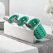 A Steril-Sil stainless steel flatware organizer with green perforated plastic cylinders holding silverware.
