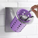 A hand placing silverware in a Steril-Sil stainless steel flatware organizer with a violet plastic cylinder inside.