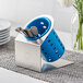 A Steril-Sil stainless steel flatware organizer with blue perforated plastic cylinder holding spoons.