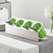 A Steril-Sil stainless steel flatware organizer with lime green perforated plastic cylinders holding silverware.