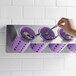 A hand placing a spoon in a violet Steril-Sil flatware organizer.