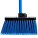 A Carlisle commercial broom with blue flagged bristles and a black handle.