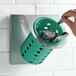 A hand placing a spoon in a Steril-Sil stainless steel flatware organizer with a green perforated plastic cylinder.