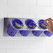 A hand holding a blue Steril-Sil stainless steel flatware organizer with purple plastic cylinders holding silverware.