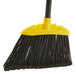 A Rubbermaid commercial broom with a black handle and yellow bristles.