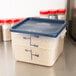 A translucent Cambro CamSquares polypropylene container with a blue lid on a counter.