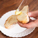 A person using a Fineline clear plastic sandwich spreader to spread butter on a piece of bread.