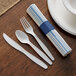 A white table set with a Hoffmaster blue and white striped napkin, EarthWise cutlery, and a plate.