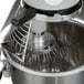 A Globe commercial stand mixer with standard accessories including a metal whisk.