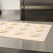A white MFG Tray proofing board with dough on a counter.