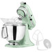 A KitchenAid Artisan stand mixer in pistachio with a bowl and attachment.