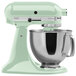 A Kitchenaid Artisan stand mixer in pistachio with a bowl attached.