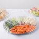 A Durable Packaging clear plastic high dome lid on a tray of vegetables and fruit in plastic containers.