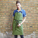 A woman wearing a green Uncommon Chef apron.