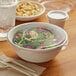 A bowl of salad in a white compostable plastic container with a flat lid.