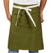 A man wearing a moss green Uncommon Chef Moxie waist apron with natural webbing.