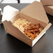 A Fold-Pak Bio-Plus-Earth paper take-out box filled with rice and meat on a table.