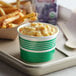 A tray with a green Choice paper cup of macaroni and cheese on it with french fries.