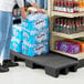 A black plastic platform with a stack of water bottles on a table in a grocery store aisle.