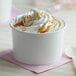 A white paper cup filled with ice cream and caramel sauce.