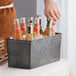 A man holding an American Metalcraft galvanized metal rectangular beverage tub with bottles of beer inside.