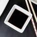 An American Metalcraft square porcelain bowl of soy sauce on a table with chopsticks.