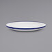 A close up of a Crow Canyon Home white enamelware plate with blue rim.