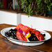 A white enamelware oval platter with black trim holding lobster and mussels on a table.