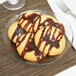A close up of a Arcoroc Fleur glass dessert plate with four cookies drizzled with chocolate.