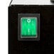 A close up of a green light on a black box with white lines.