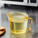 A Cambro high heat amber plastic measuring cup with liquid in it.