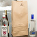 A Duro brown paper bag with a clear glass bottle and two clear glass bottles filled with liquor.