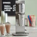 A AvaMix milkshake machine with a glass of milkshake in it on a counter.