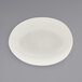 A white semi-matte scallop oval porcelain bowl on a gray surface.