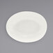 A white scalloped oval porcelain bowl on a gray surface.