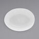 A semi-matte white oval porcelain bowl with a round center on a gray surface.