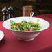 A white porcelain CAC mixing bowl filled with salad on a table.