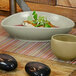 A Front of the House Tides oval porcelain bowl filled with food on a wooden table.