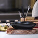 A black Front of the House Tides oval porcelain bowl on a wood board.