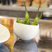 A close-up of a white Front of the House Tides scallop round porcelain bowl filled with green peppers.
