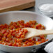 A wooden spoon in a pan of diced carrots and celery.