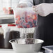 A gloved hand using a Cambro plastic colander to rinse strawberries and blueberries.