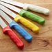 A group of Dexter-Russell bread knives with colorful handles.