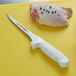 A Dexter-Russell narrow boning knife next to a piece of chicken.
