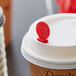 A Royal Paper Stix To Go red coffee stirrer in a coffee cup with a lid.